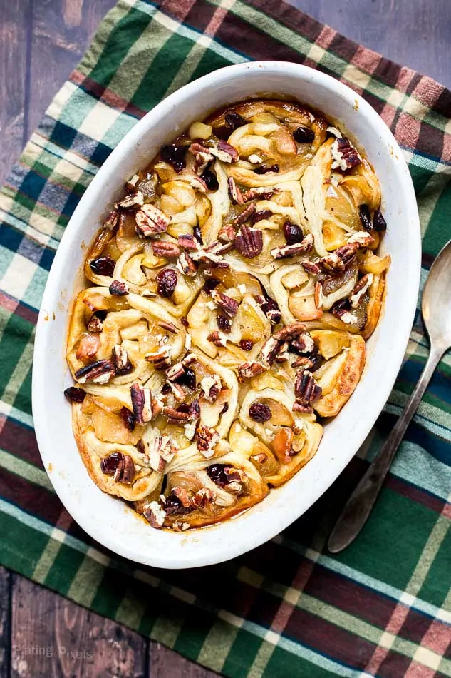 Apple pie puff pastry rolls with apples, raisins, and cinnamon in a baking dish.