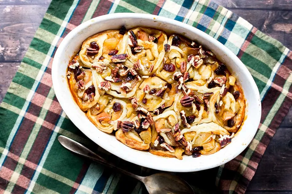 Apple pie puff pastry rolls with caramelized apples and pecans in a baking dish.