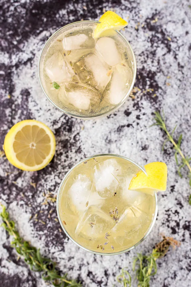 Refreshing lavender lemon cocktail with ice and lemon wedge garnish.