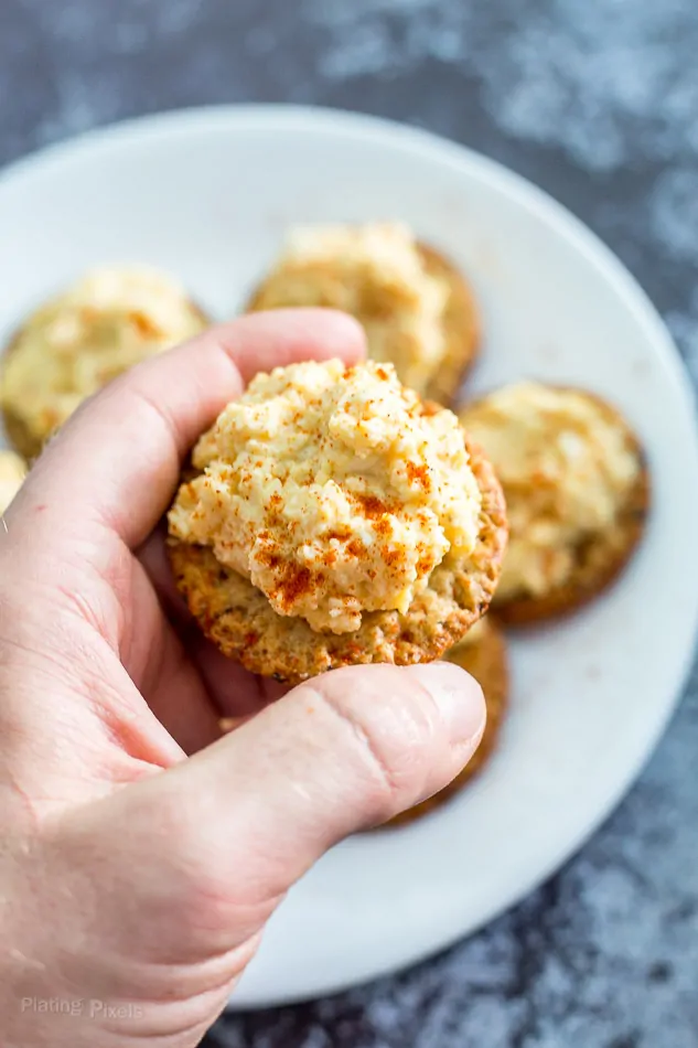 Close-up of deviled egg cracker bites on a white plate, perfect for party snacks.