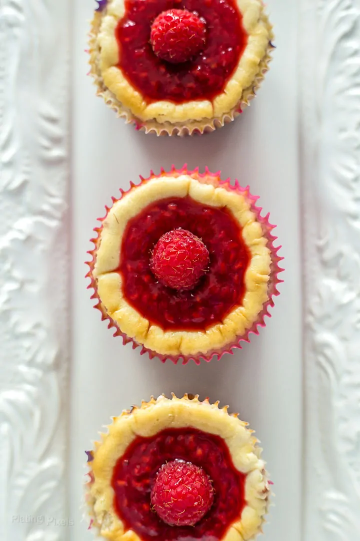 Mini cheesecakes with raspberry topping and fresh raspberries on top.
