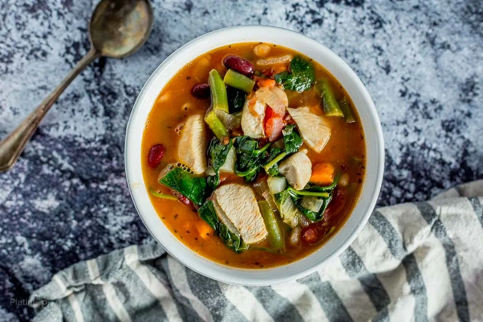Hearty chicken minestrone soup with vegetables in a white bowl, perfect for a comforting meal.