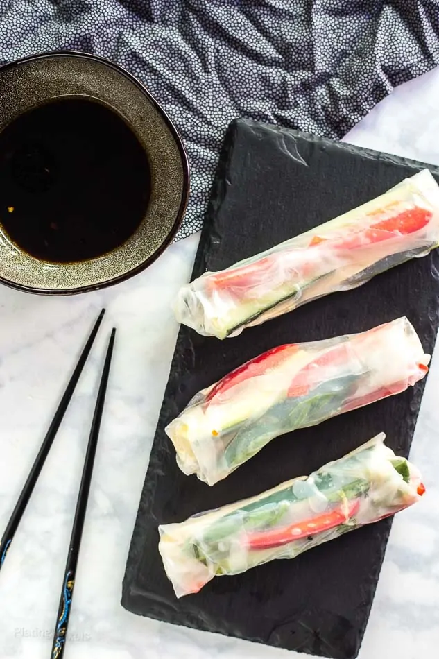Fresh vegan Vietnamese tofu spring rolls with vegetables on black slate.