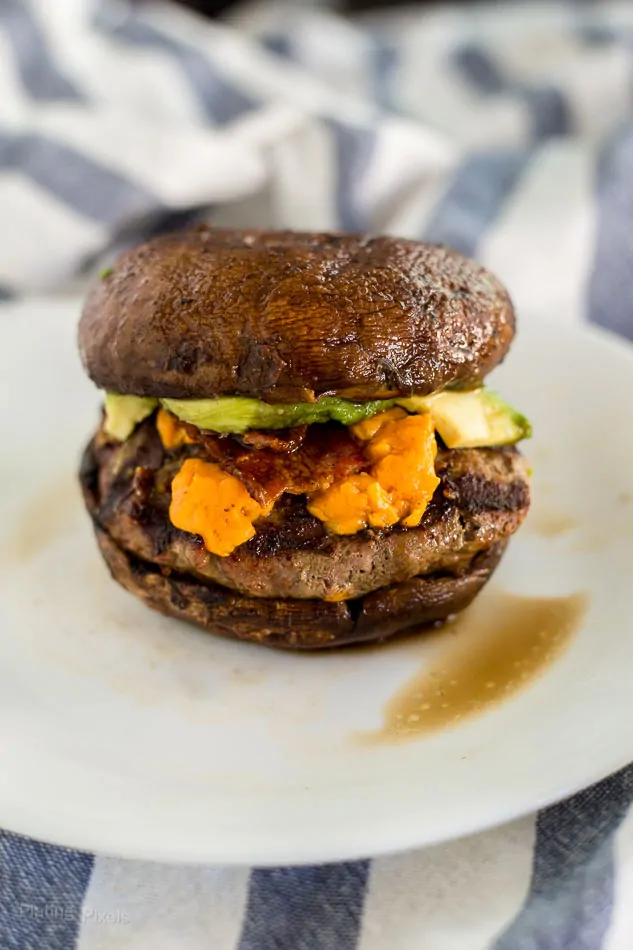 Keto cheese burger with portobello mushroom buns and avocado slices.