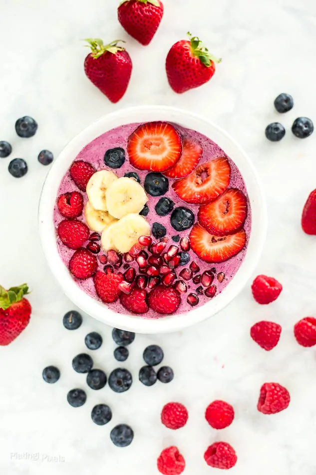 Colorful smoothie bowl with strawberries, blueberries, raspberries, and banana slices.