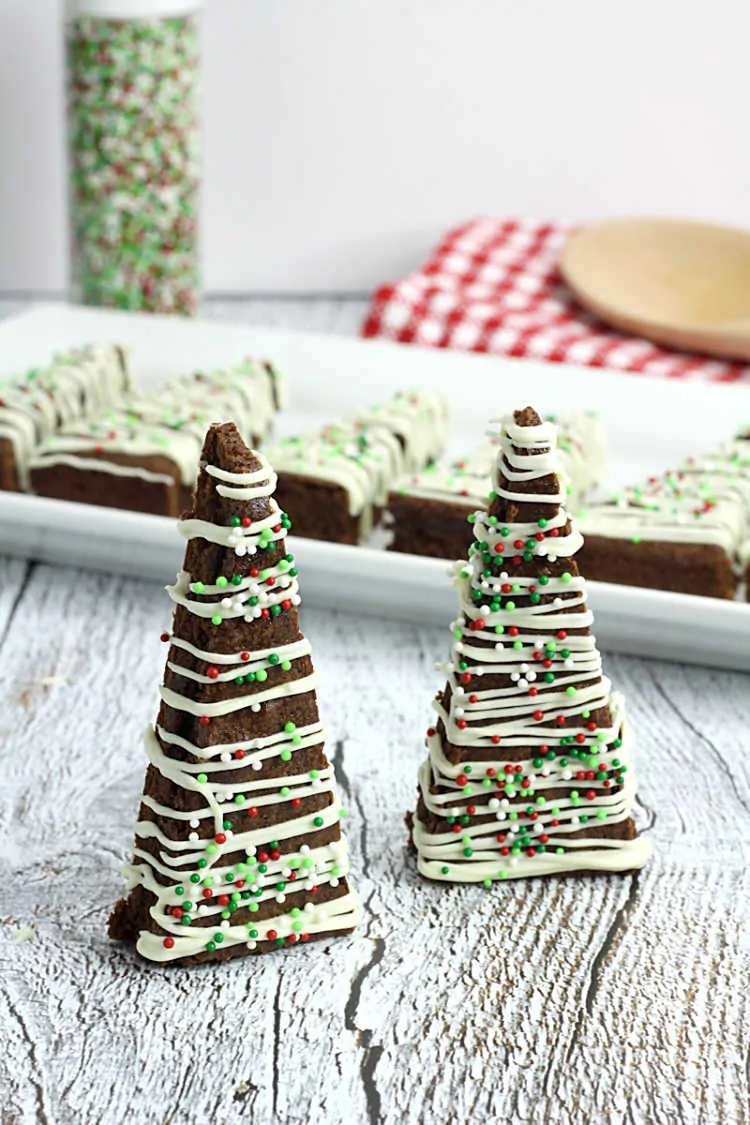 Decorated Christmas tree cookies with white and green icing and sprinkles.
