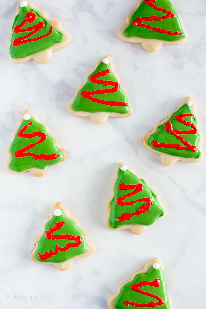 Festive Christmas tree cookies decorated with green icing and red icing garland.