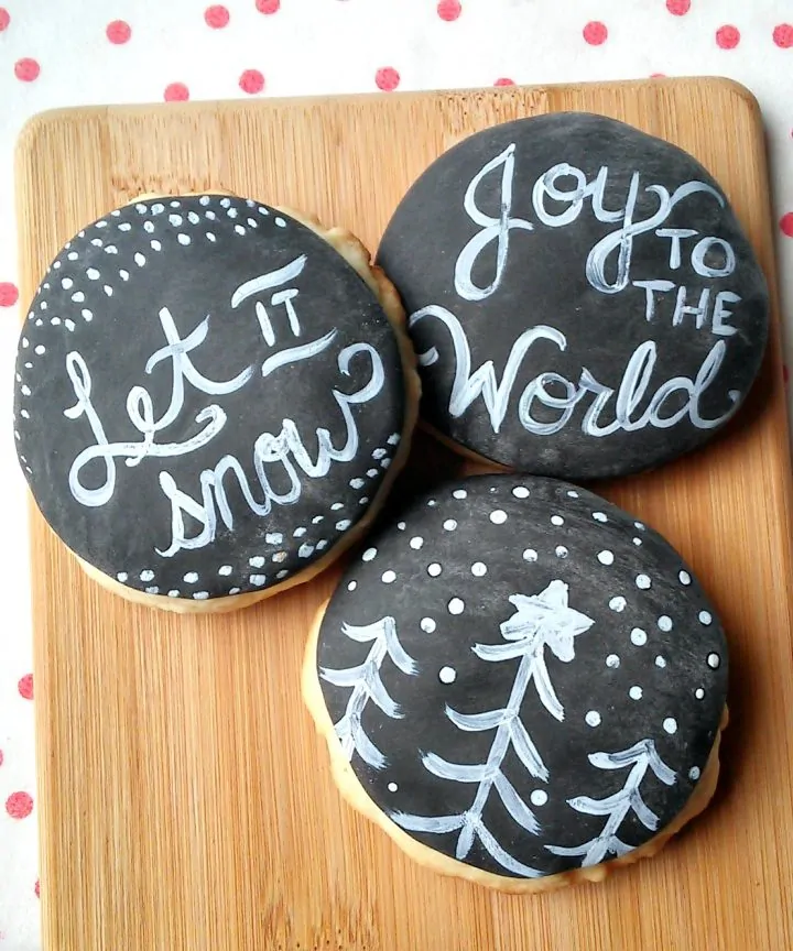 Festive decorated cookies with chalkboard-style messages and designs for Christmas.