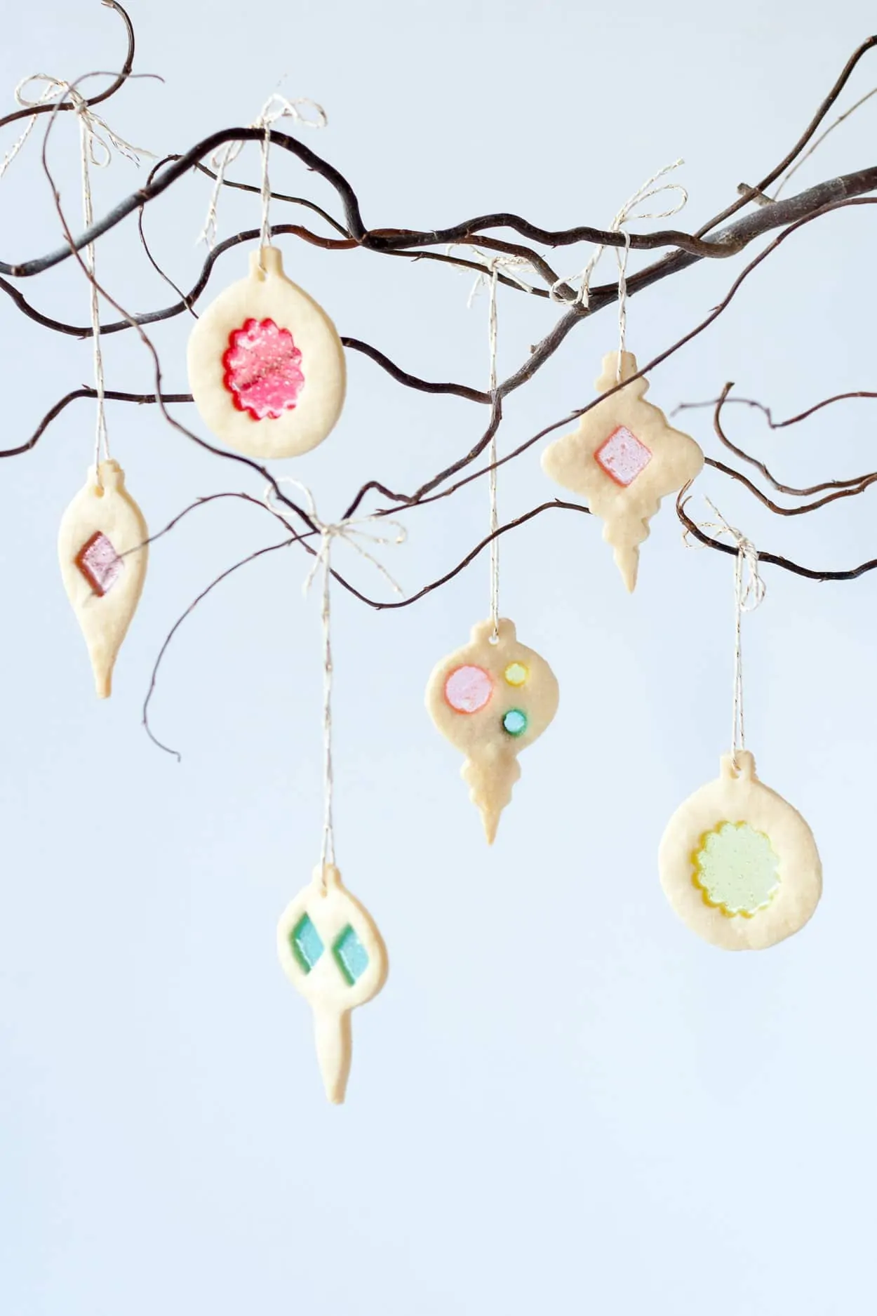 Festive decorated cookies hanging on a branch for Christmas celebration.