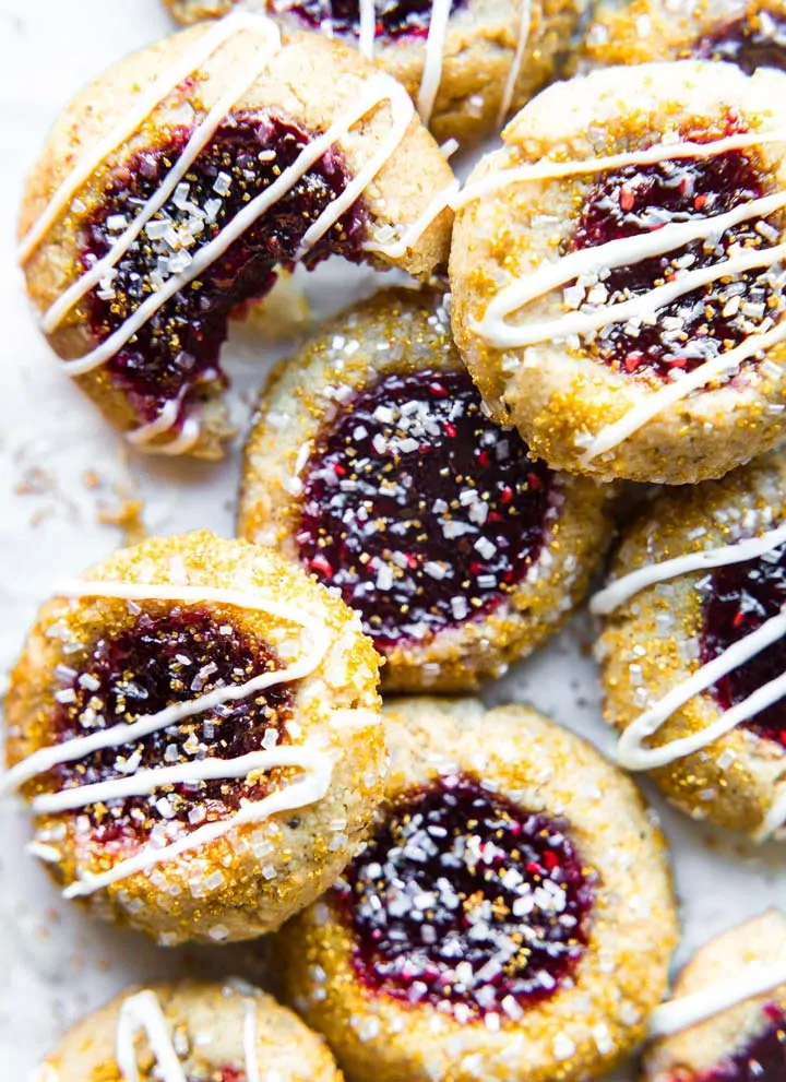 Festive decorated cookies with jam filling and white drizzle for holiday treats.