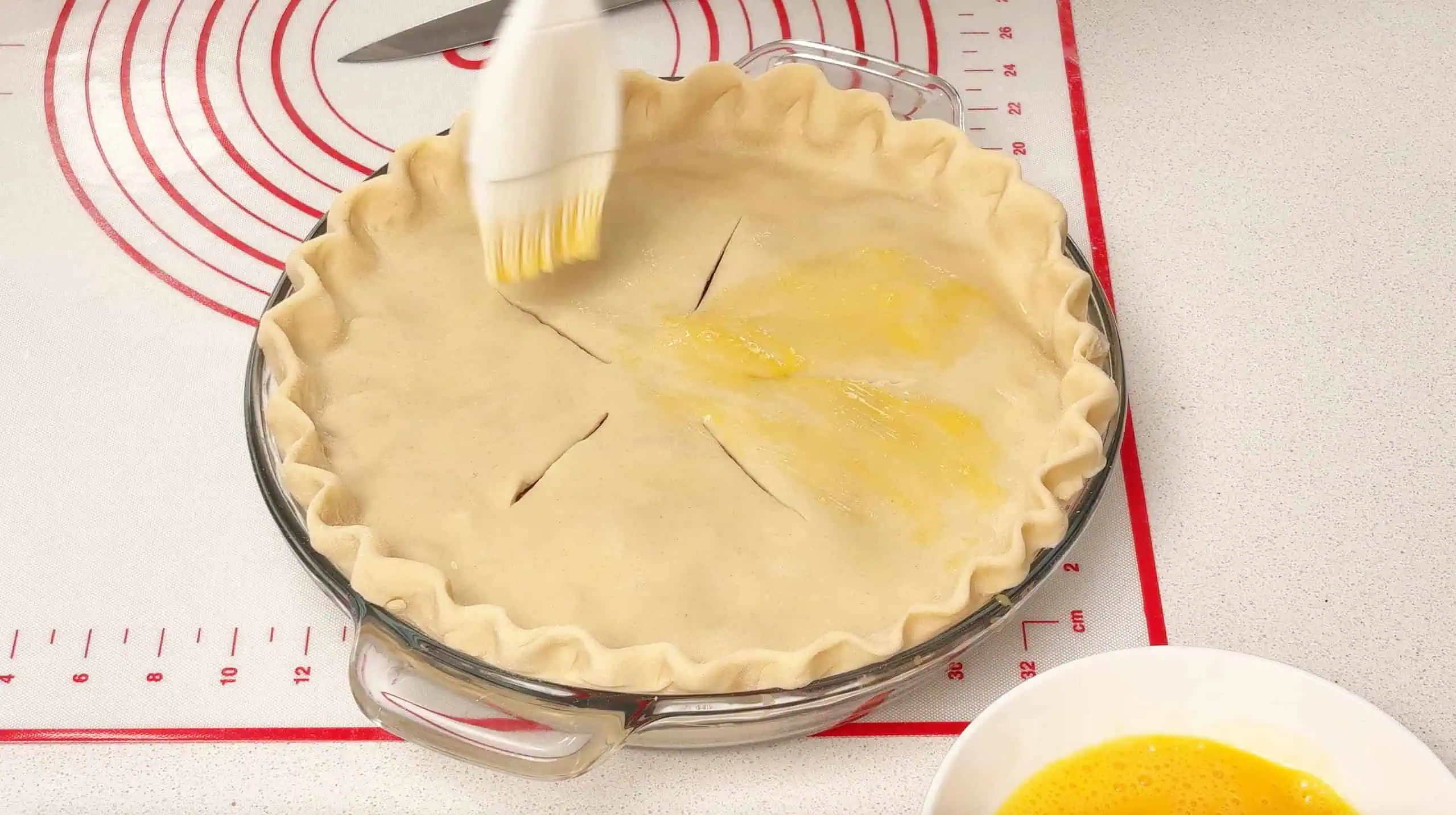 brushing egg wash on top of apple pie crust Brushing egg wash on top of apple pie crus