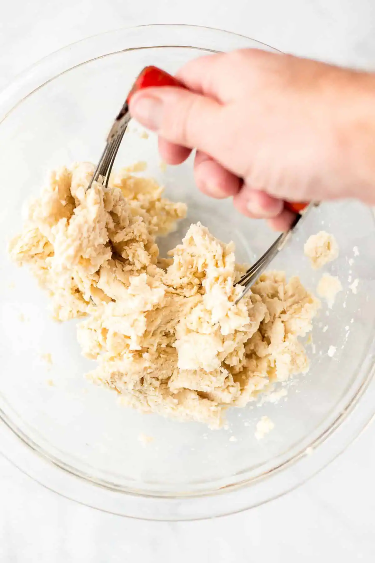 mixing dough for apple pie in a bowl with pastry cutter Preparing pie crust dough for an apple pie with a pastry cutter