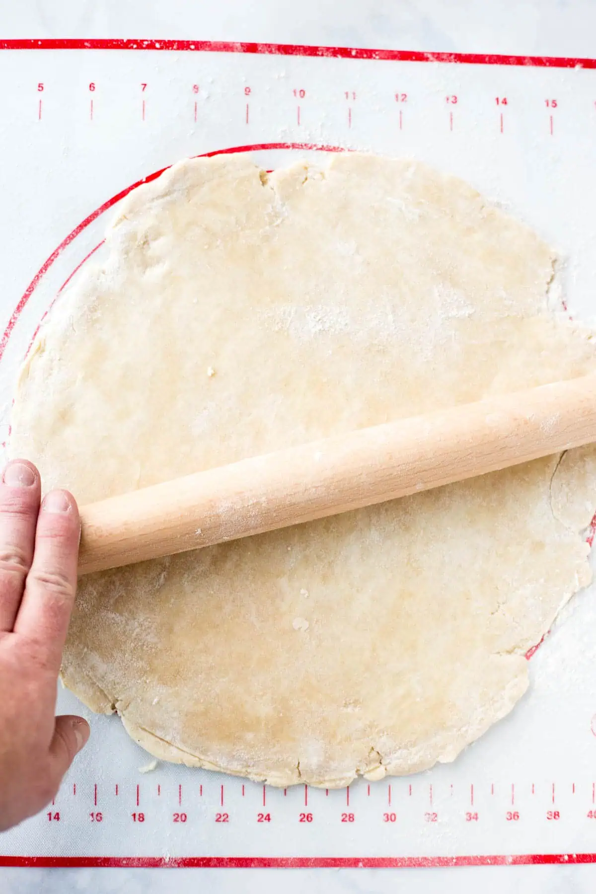 using a rolling pin to roll pie crust Rolling out pie dough on a baking mat for apple pie with no lattice crust.