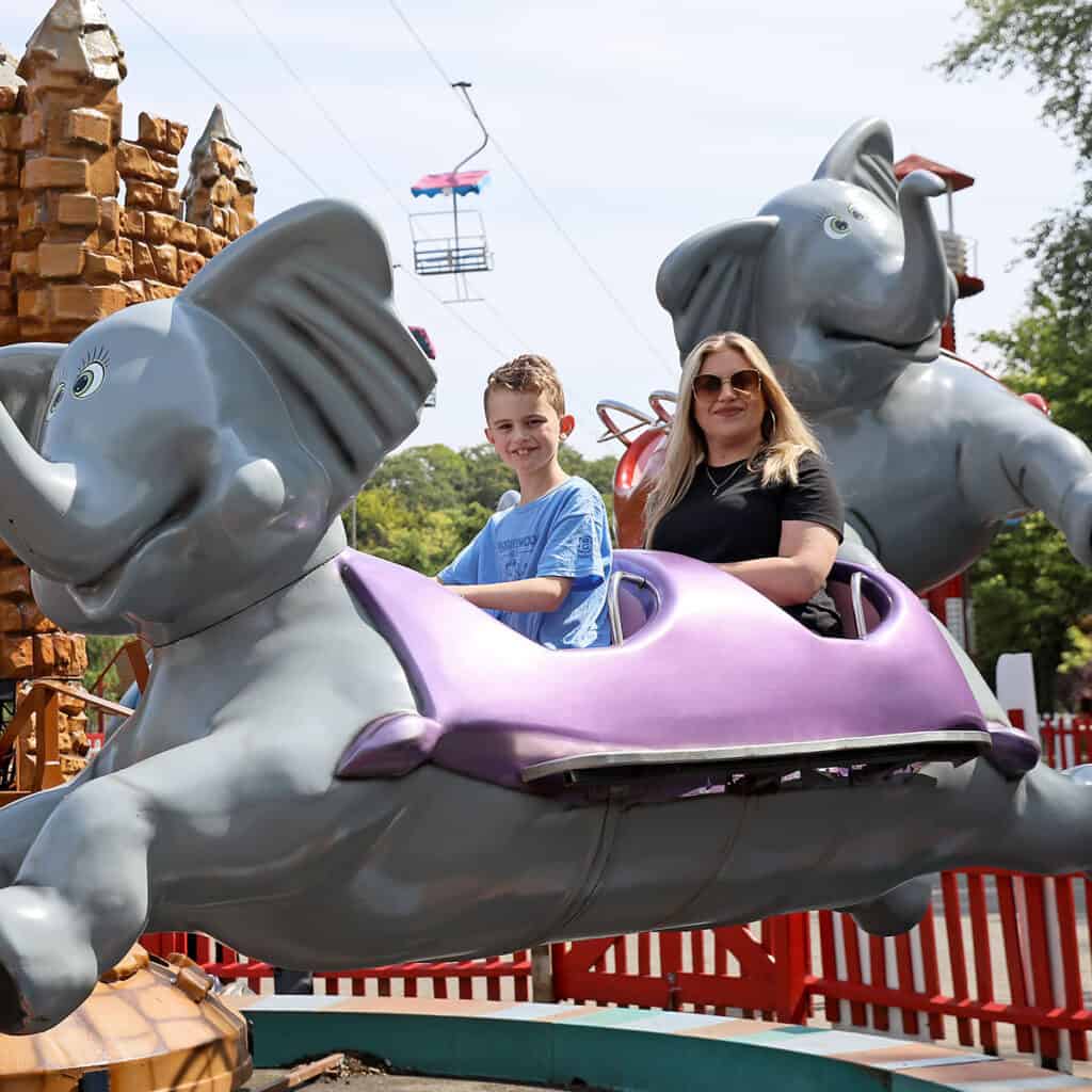 Woman and young boy on elephant themed theme park ride