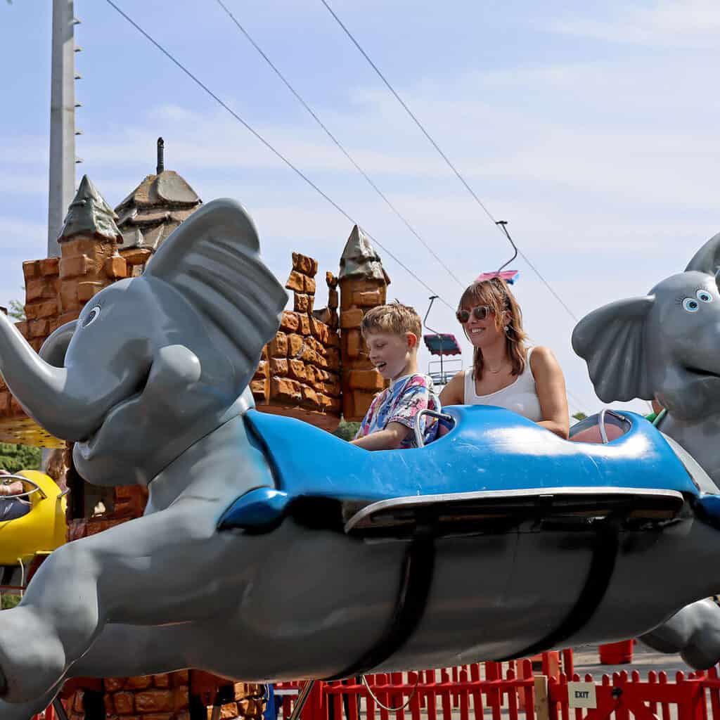 Woman and young boy on elephant themed theme park ride