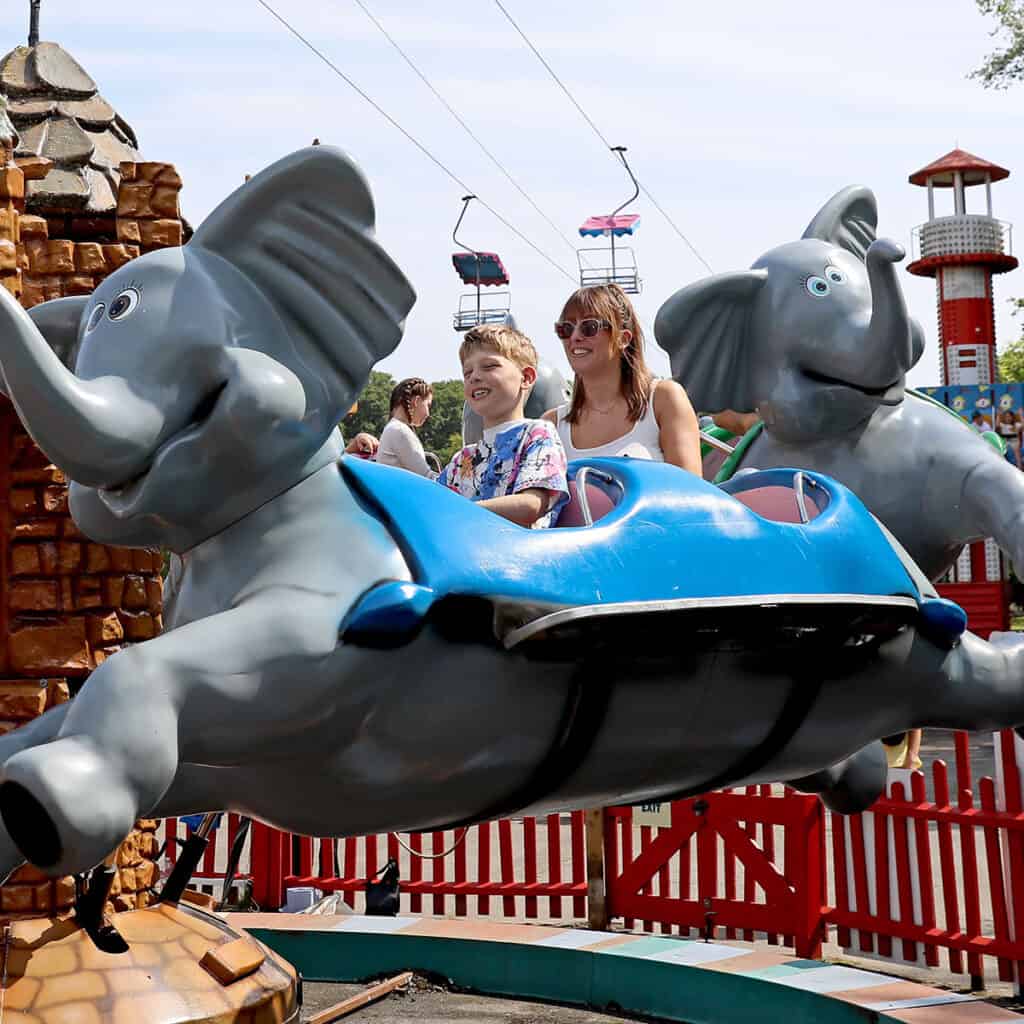 Woman and young boy on elephant themed theme park ride