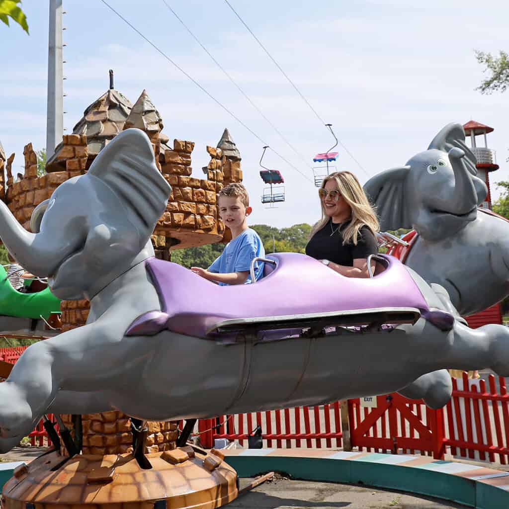 Woman and young boy on elephant themed theme park ride