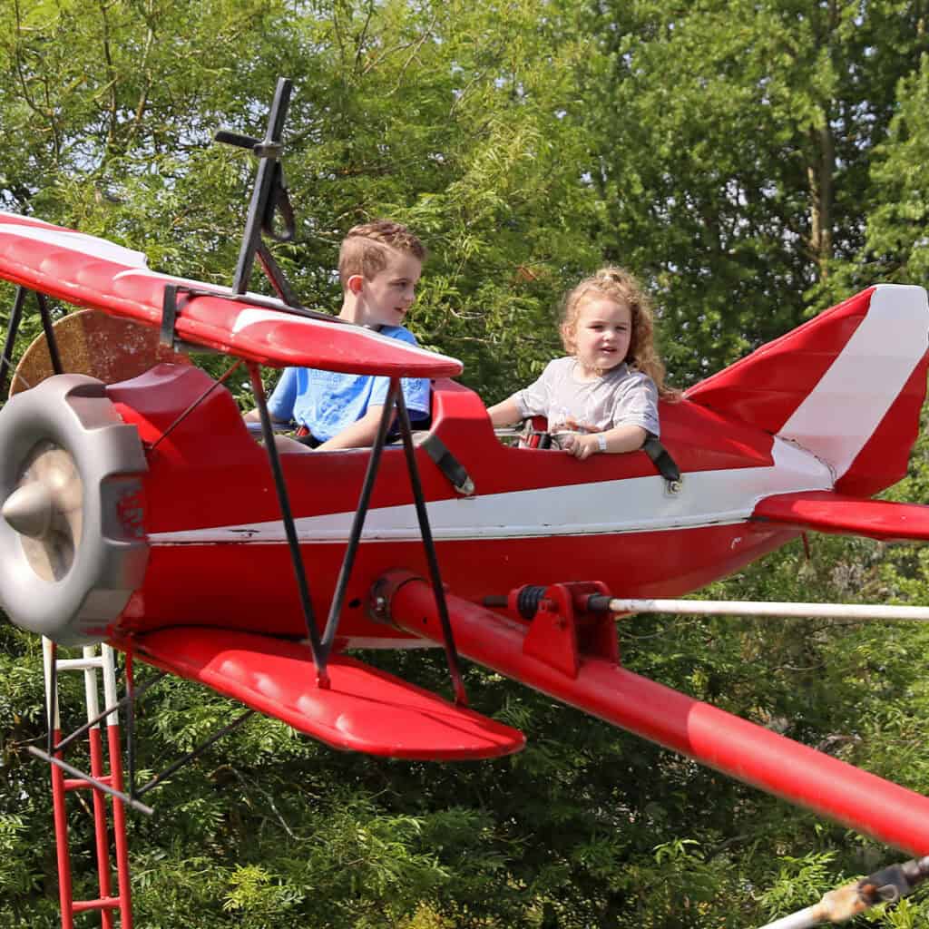 Young boy and young girl on aeroplane themed amusement park ride