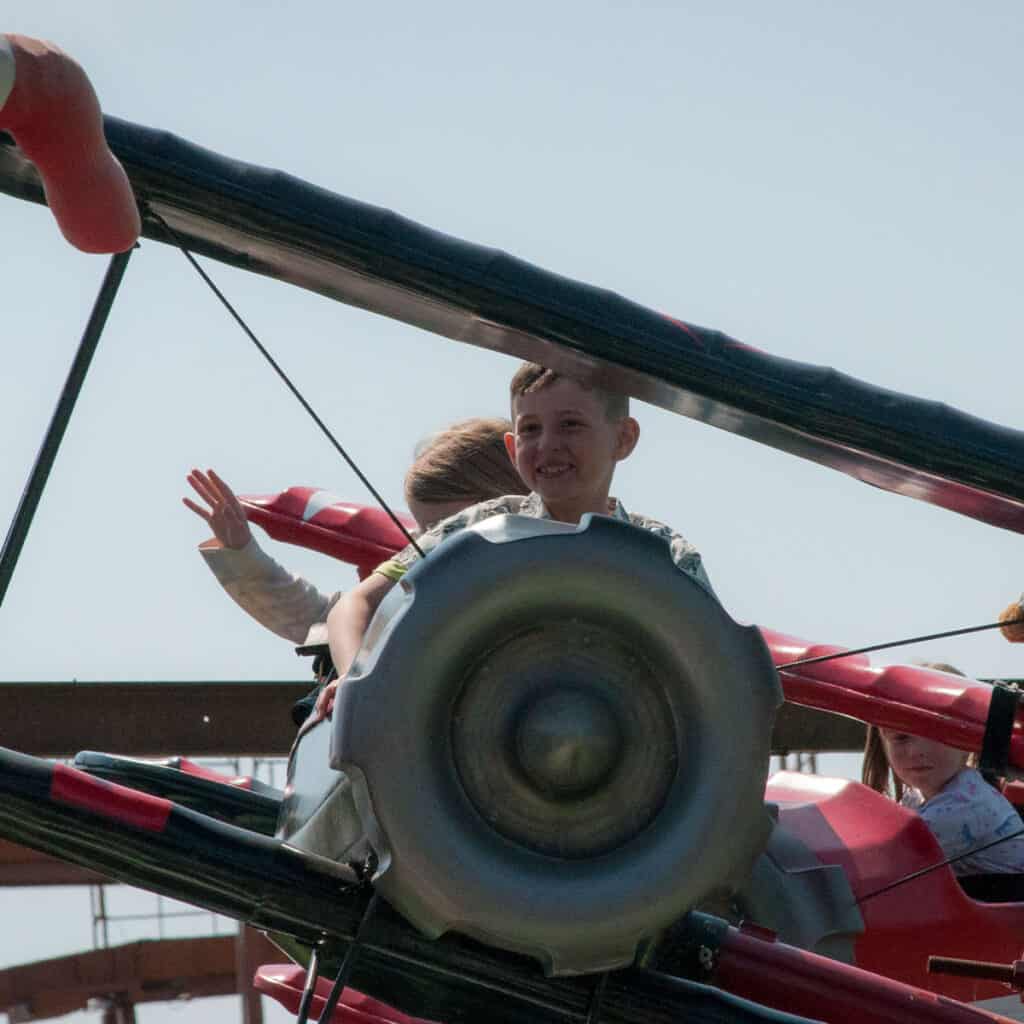 Young boy and young girl on aeroplane themed amusement park ride
