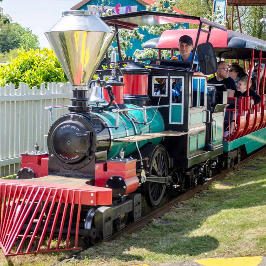 Green and red passenger train at a theme park