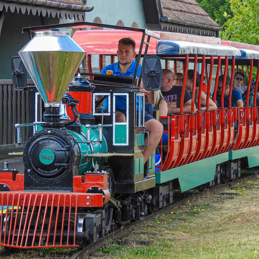 Green and red passenger train at a theme park