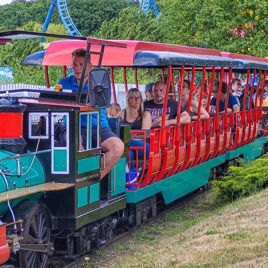 Green and red passenger train at a theme park