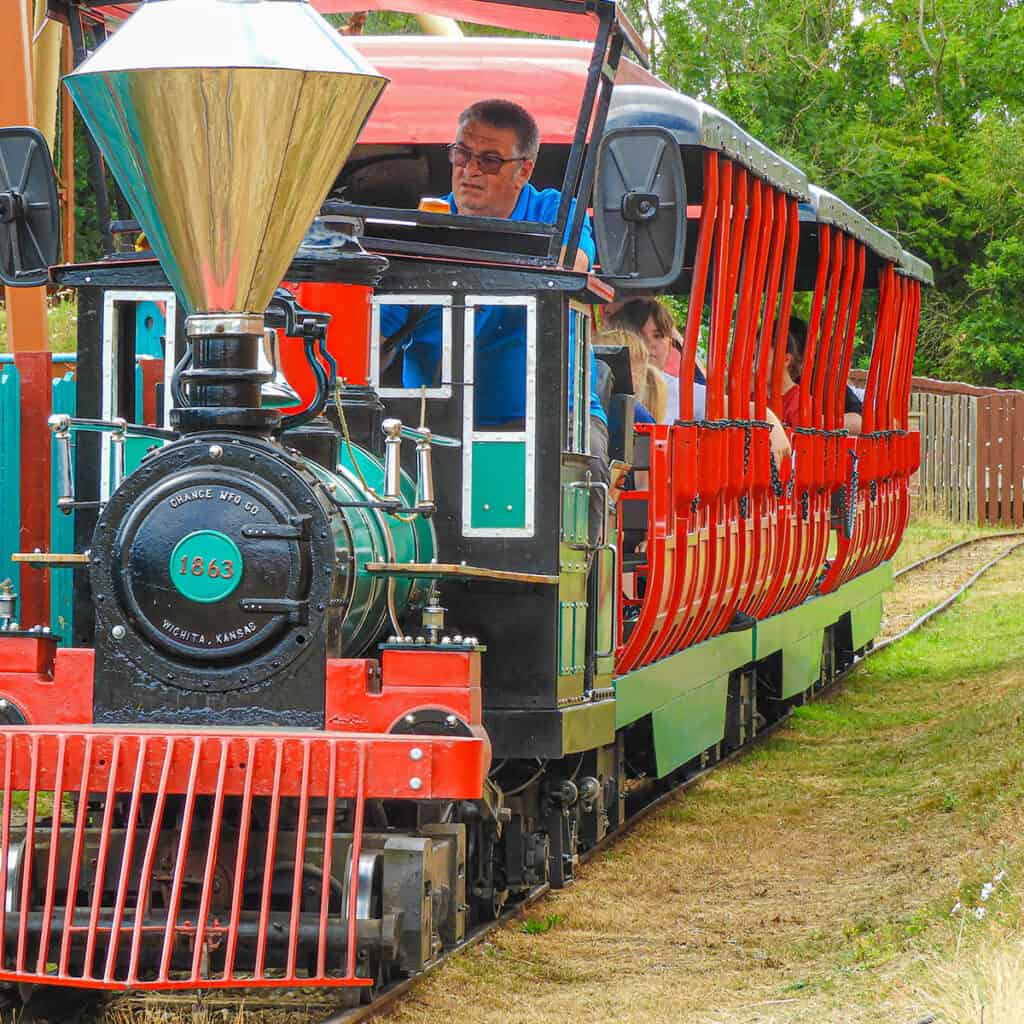 Green and red passenger train at a theme park