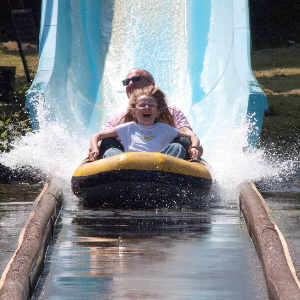 Man and young girl on a dinghy on a water slide