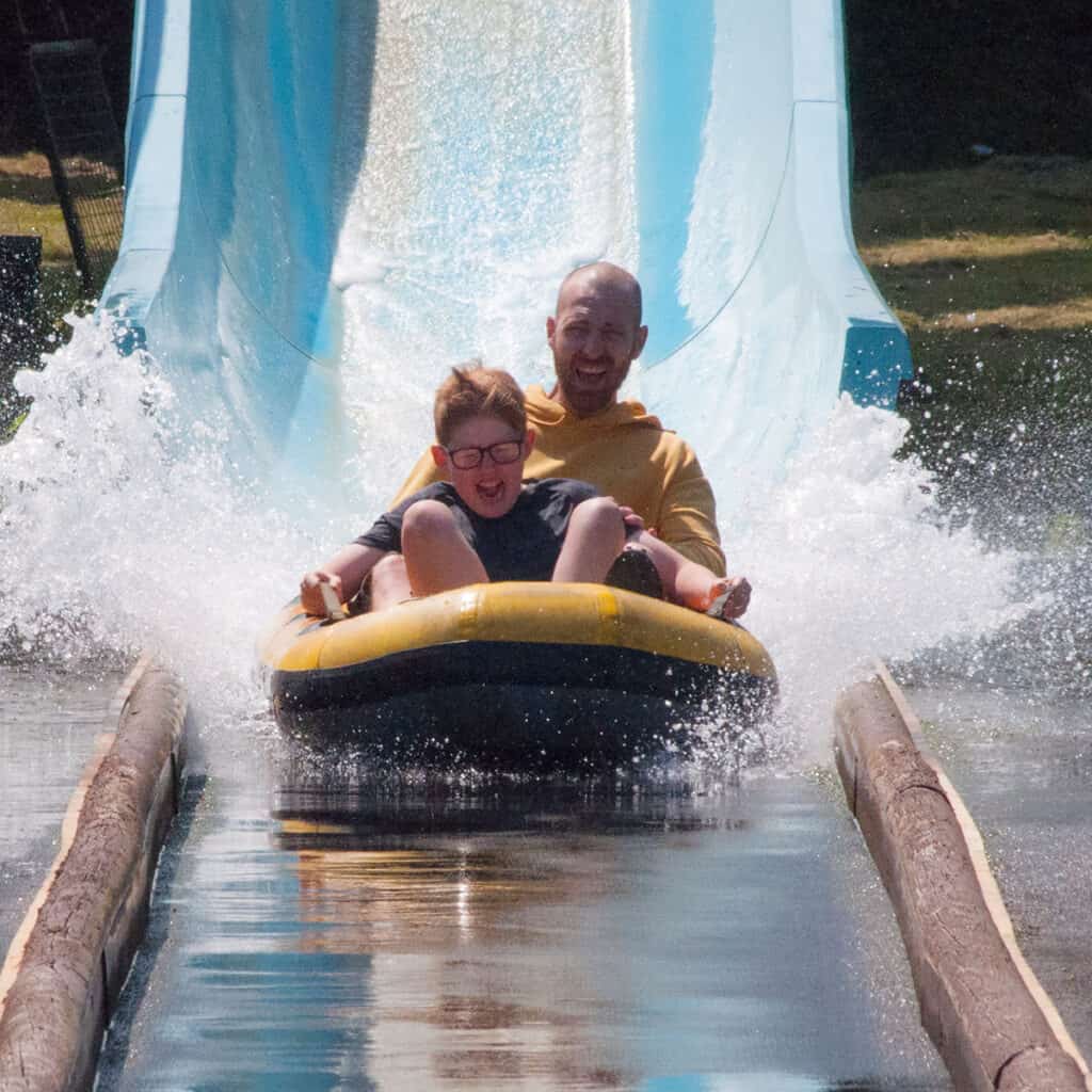 Man and young boy on a dinghy on a water slide