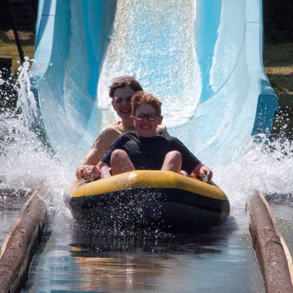 Two young boys on a dinghy on a water slide