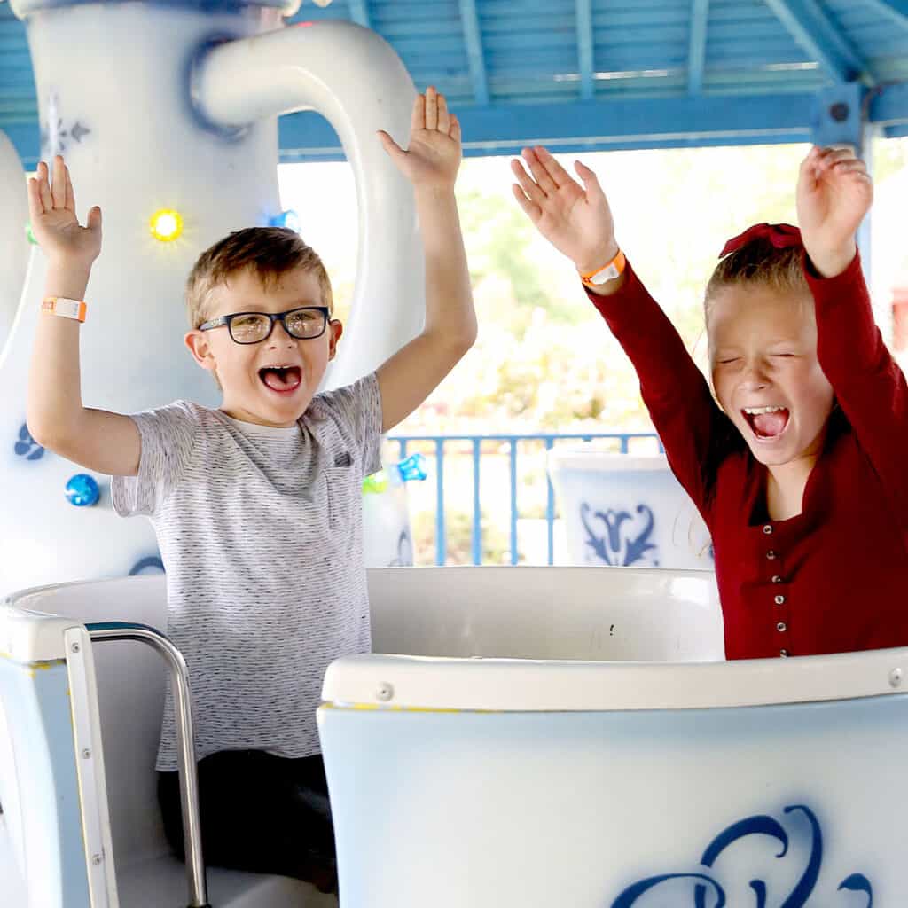 Young girl and young boy excited on a teacups ride