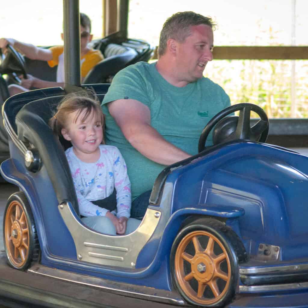 Main and young girl in blue dodgems car