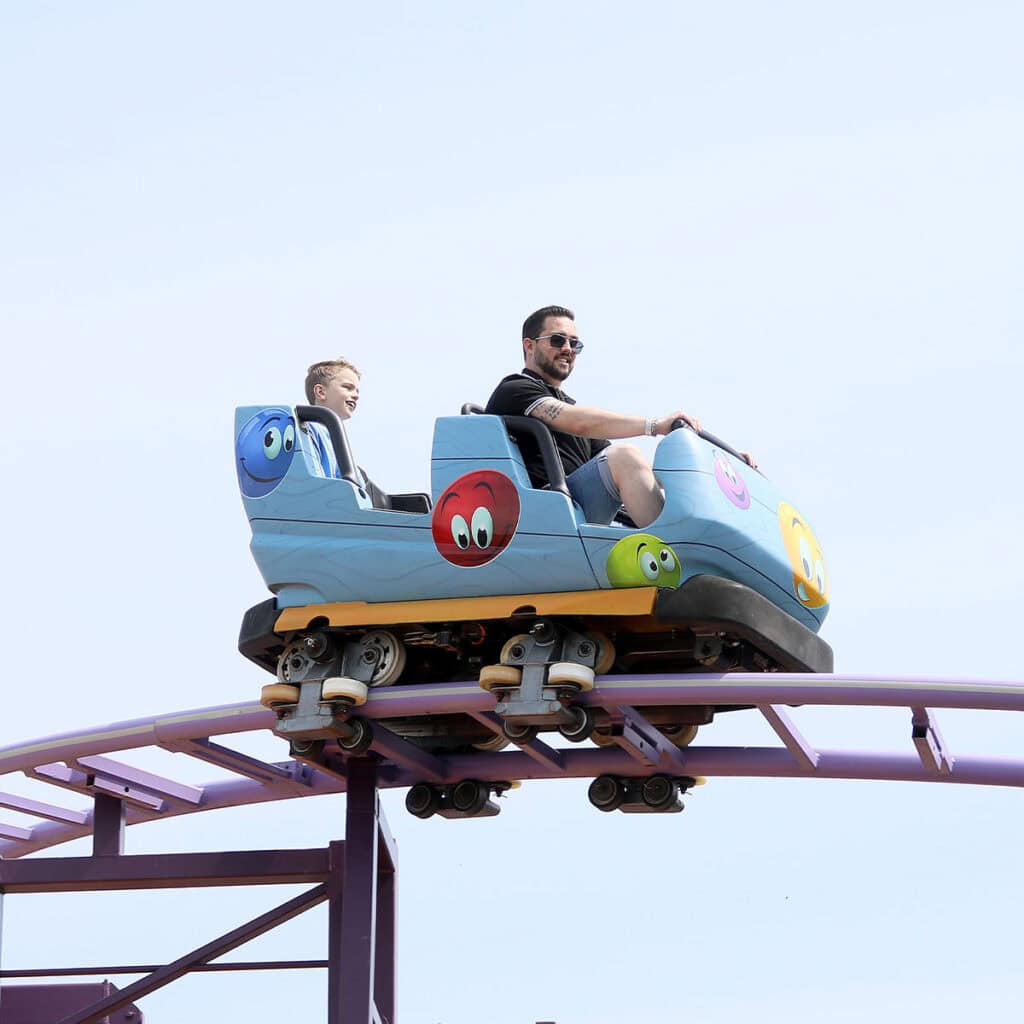 Man and a young boy in a blue rollercoaster cart.