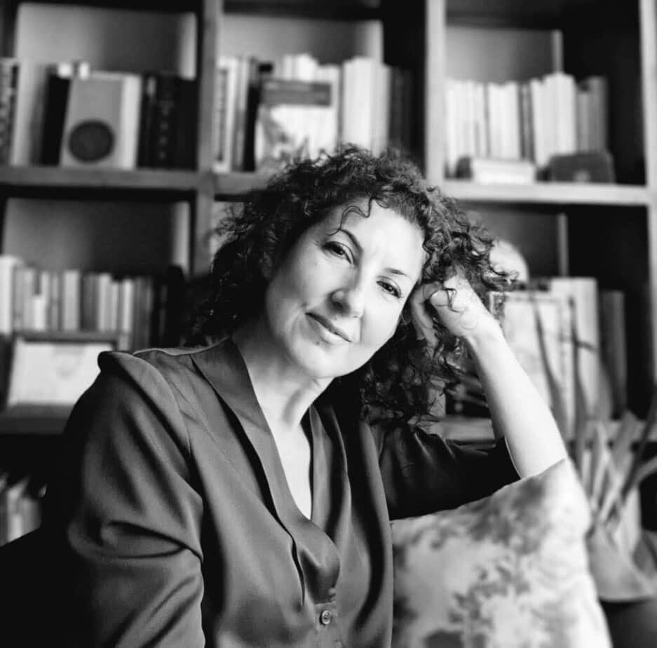 1. Black and white portrait of a woman in front of a bookshelf filled with poetry books.