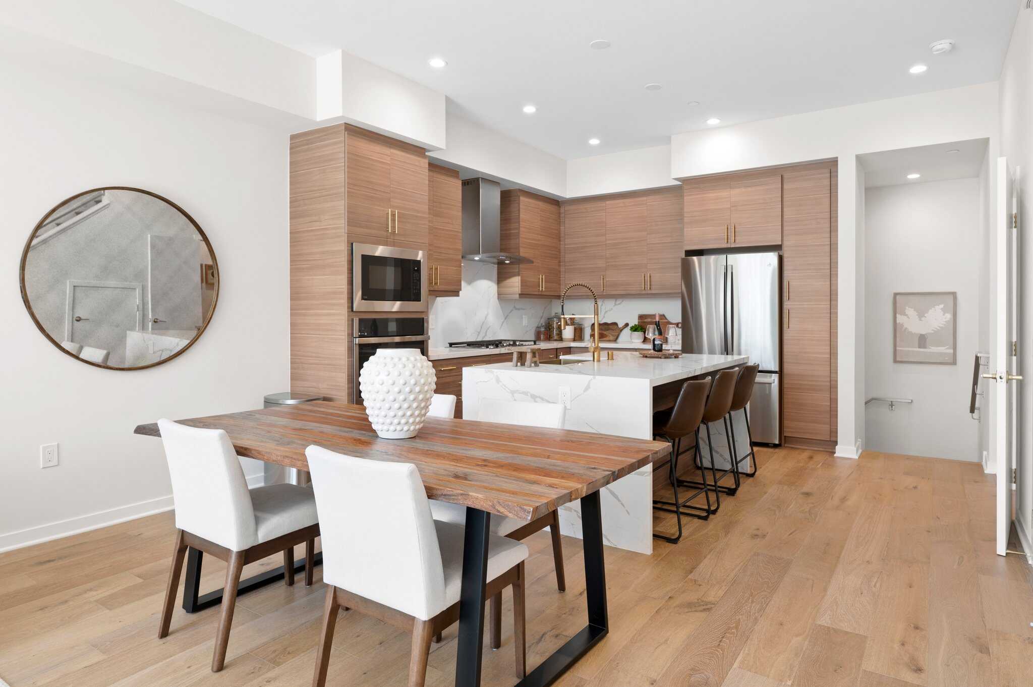 Contemporary kitchen and dining area at Point North Park apartment community in San Diego, California, featuring modern design, wood cabinetry, marble countertops, and upscale amenities.