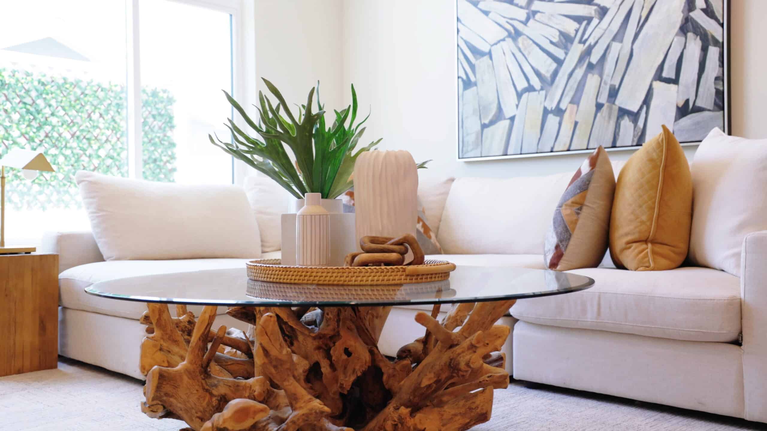 Bright living room with modern decor and ocean-inspired art artwork, featuring ample natural light, neutral-toned sofa with accent pillows, and a unique coffee table made from driftwood at Point North Park, San Diego.
