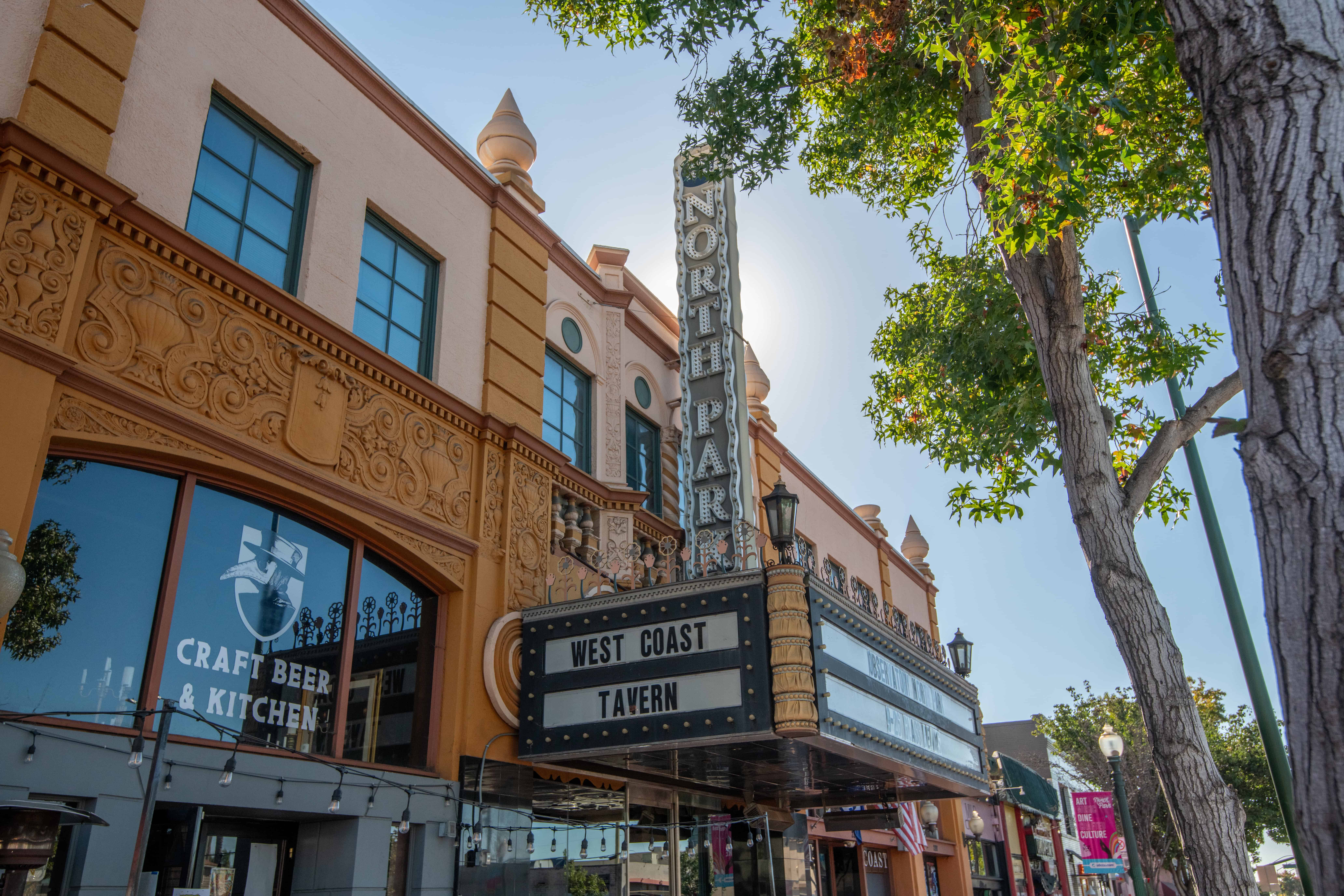 Vibrant streetscape in Point North Park, San Diego featuring the historic West Coast Tavern with classic marquee signage, decorative building facades, and lively local businesses in a charming urban neighborhood.