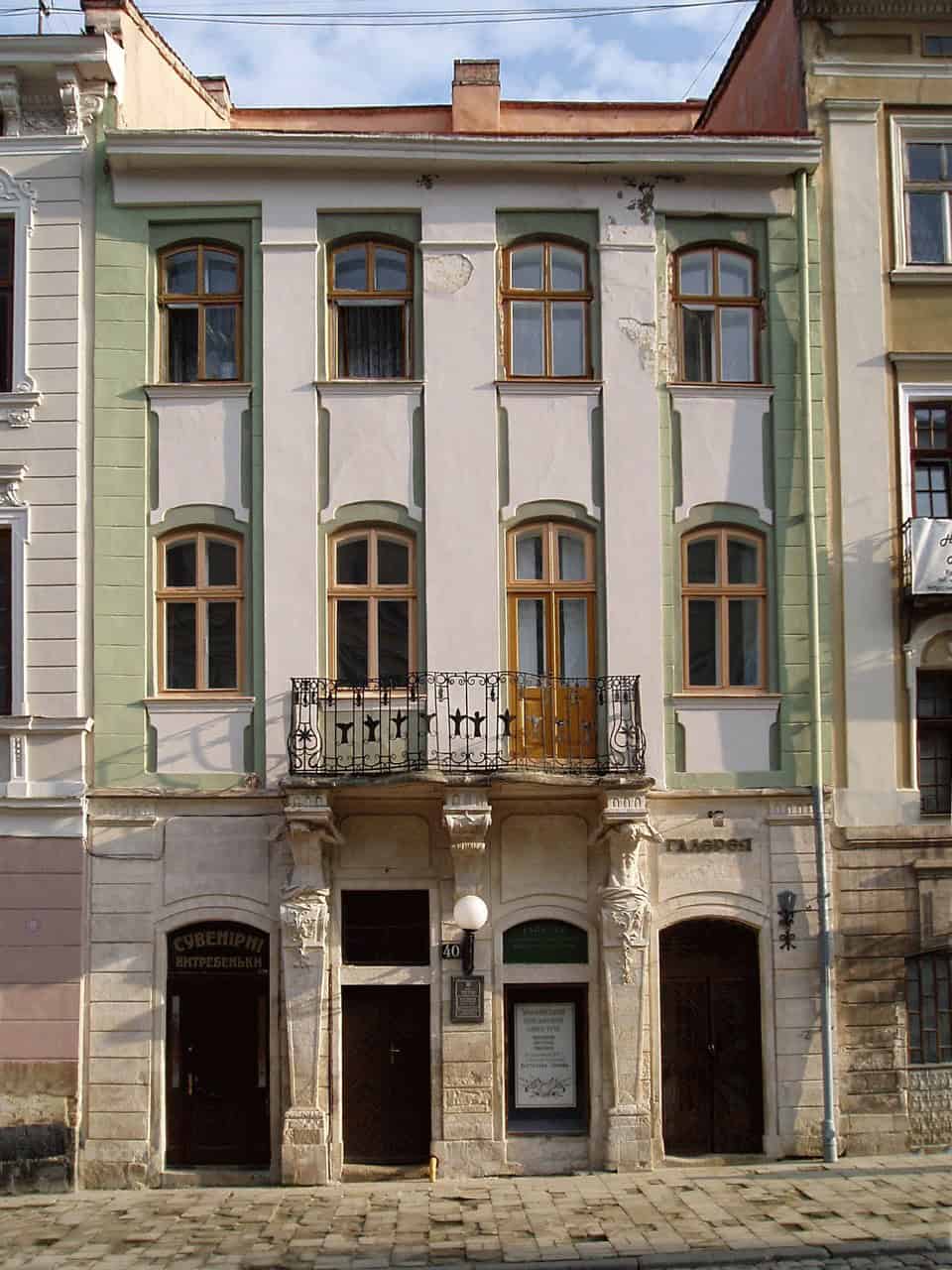 Фасад історичної будівлі в центрі міста, з балконом і старовинними вікнами.