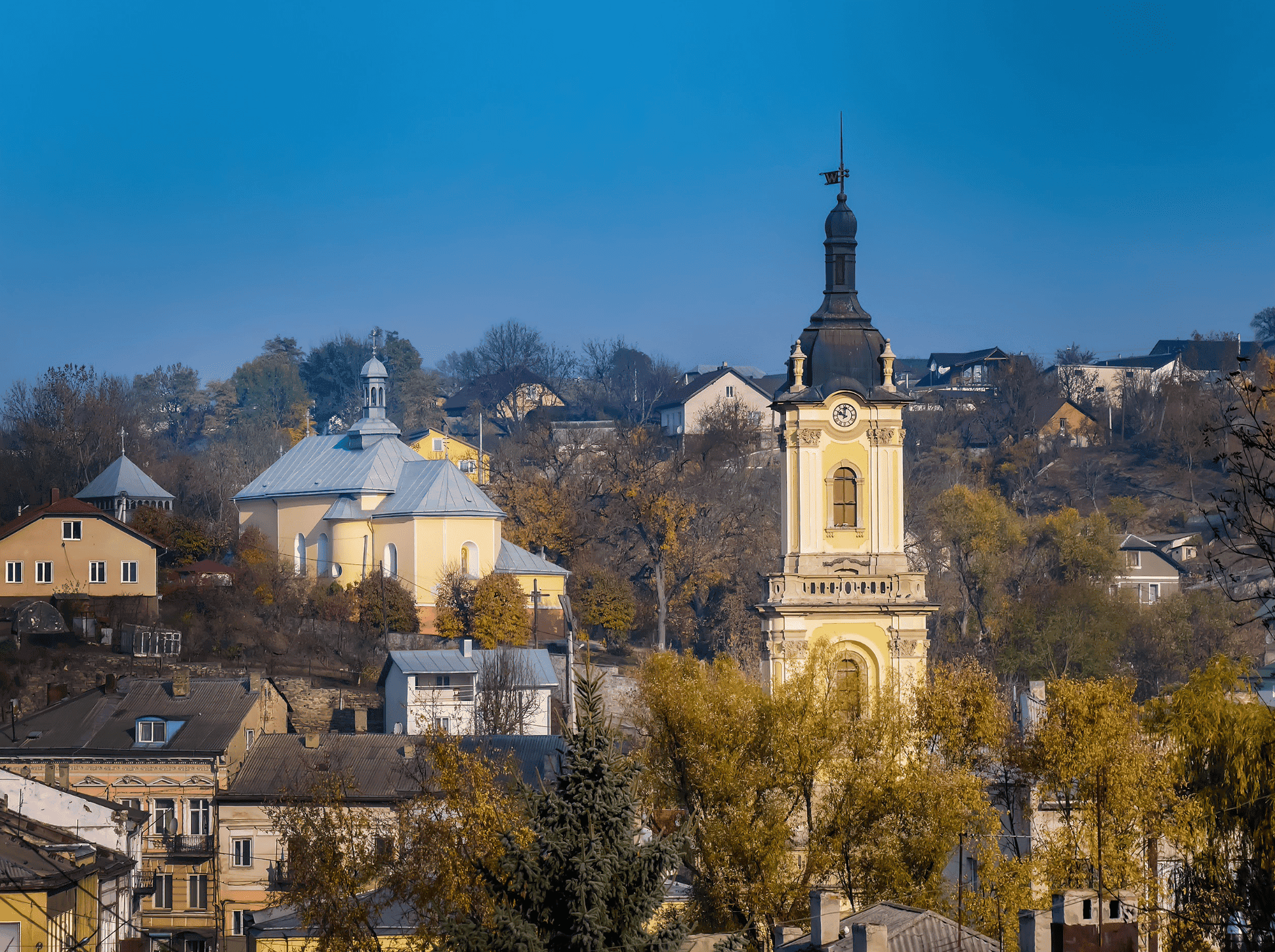 Історичний краєвид з церквою та дзвіницею на тлі осіннього міста.