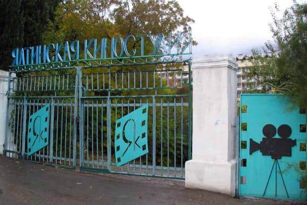 Вхід до Ялтинської кіностудії художніх фільмів з металевим парканом і логотипом.