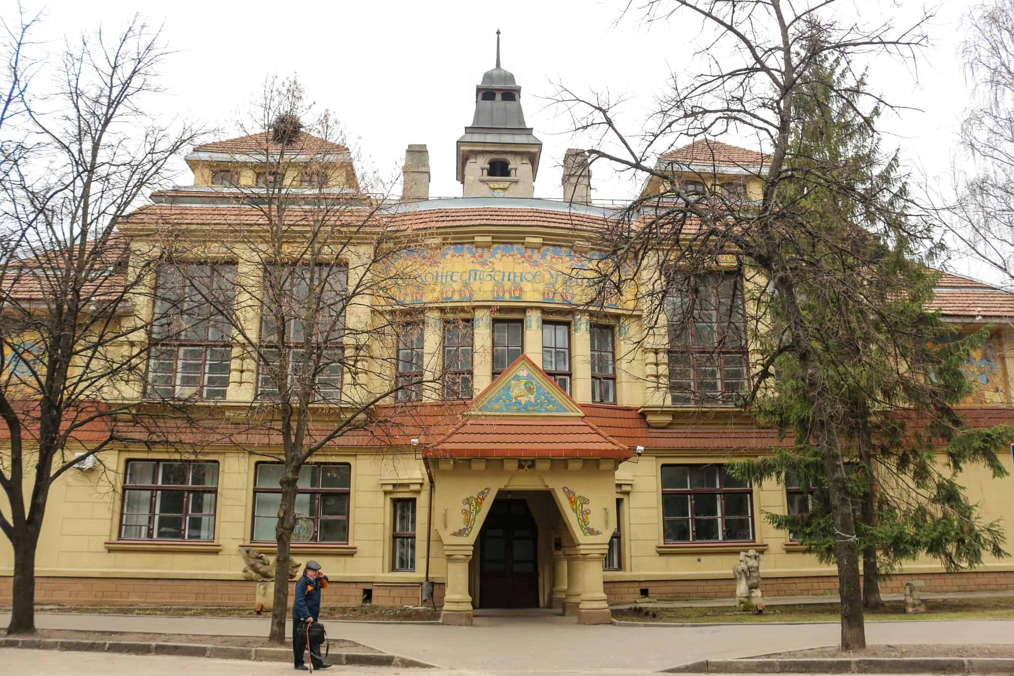 Історична будівля українського архітектурного модерну з деревами навколо.