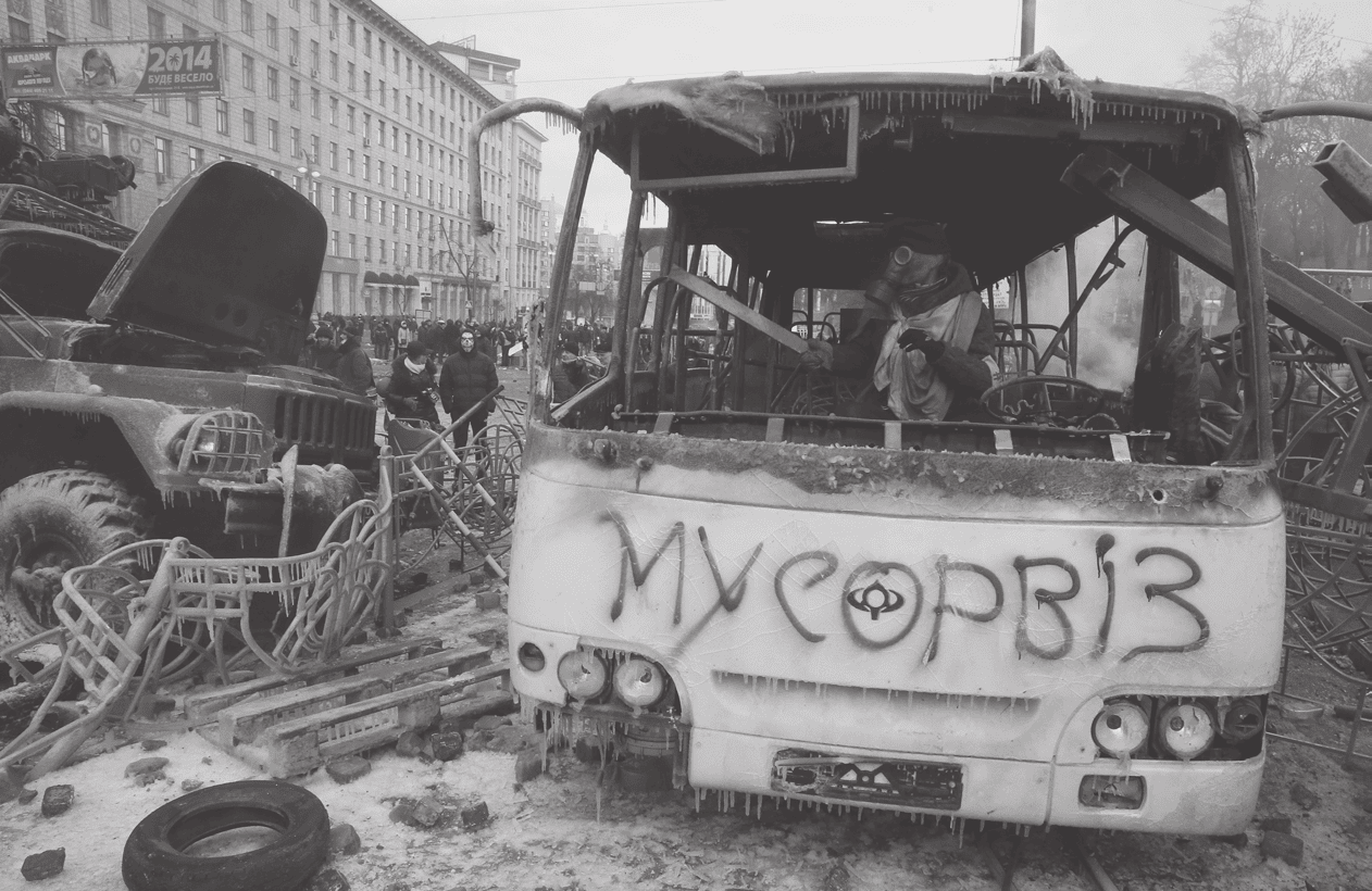 Зруйнований автобус з написом МУСОРВІЗ, руйнування та пошкодження навколо.