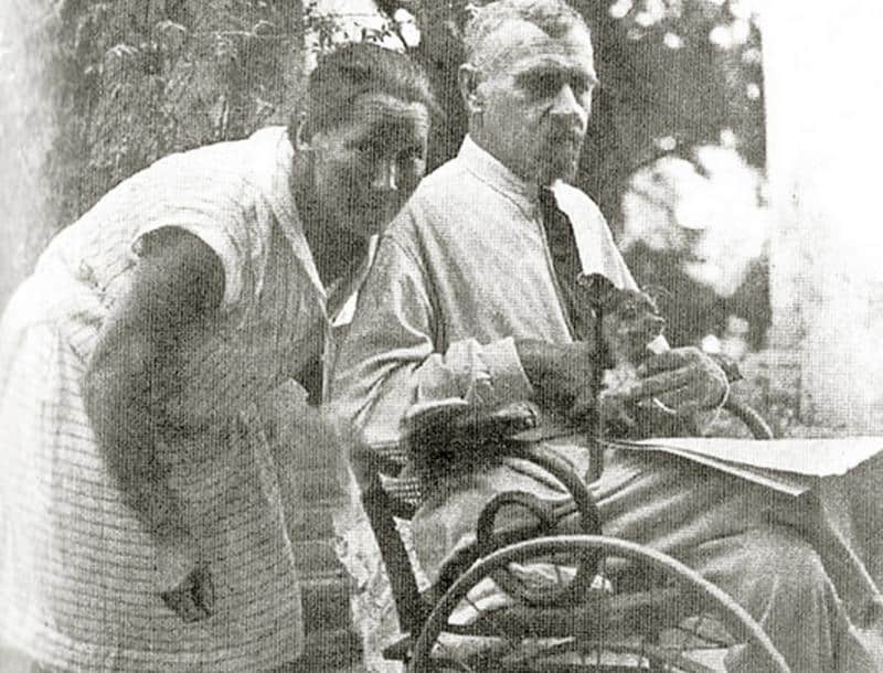 Двоє людей біля дерева, один у інвалідному візку, історична фотографія.