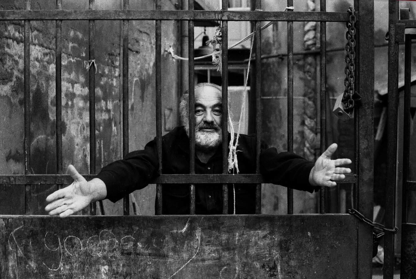 Чоловік у клітці з відкритими руками, символізуючи свободу або боротьбу.