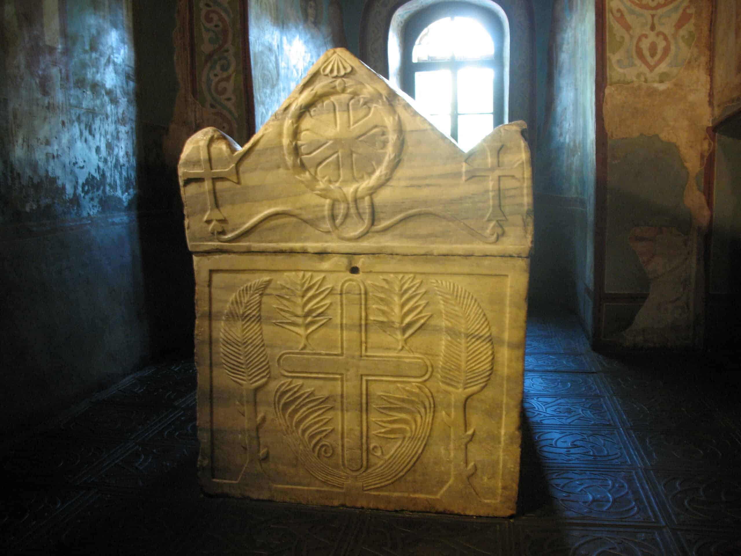 Древній камінь з хрестом і символами у церкві, історична реліквія.