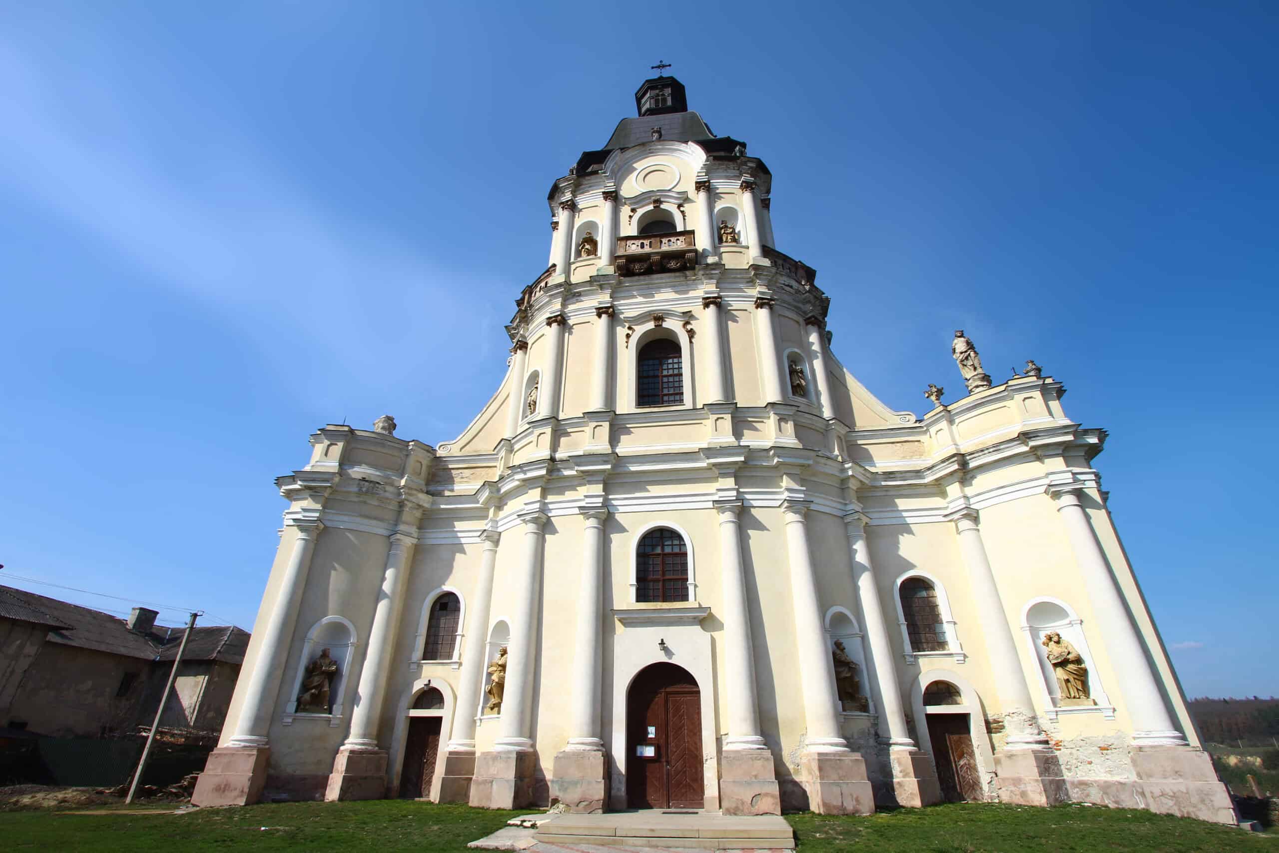 Барокова церква з високою дзвіницею на фоні ясного неба.