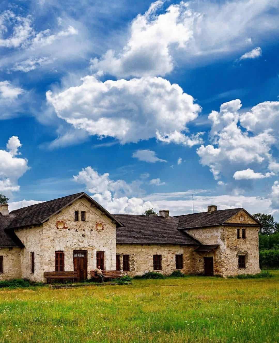 Старовинний будинок на фоні яскравого неба з хмарами.