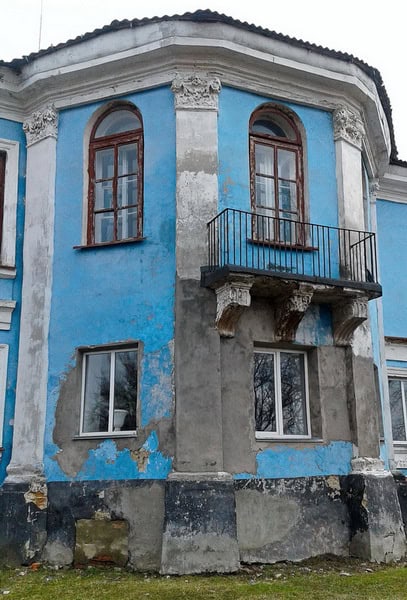 Руїни старовинної будівлі з синьою фарбою та балконом у Чорноострівецькому палаці.