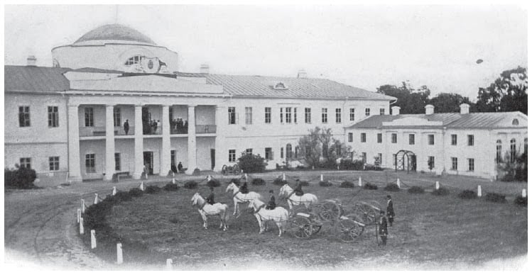 Історична фотографія з кінця XIX - початку XX століття з будівлею та кіньми на передньому плані.