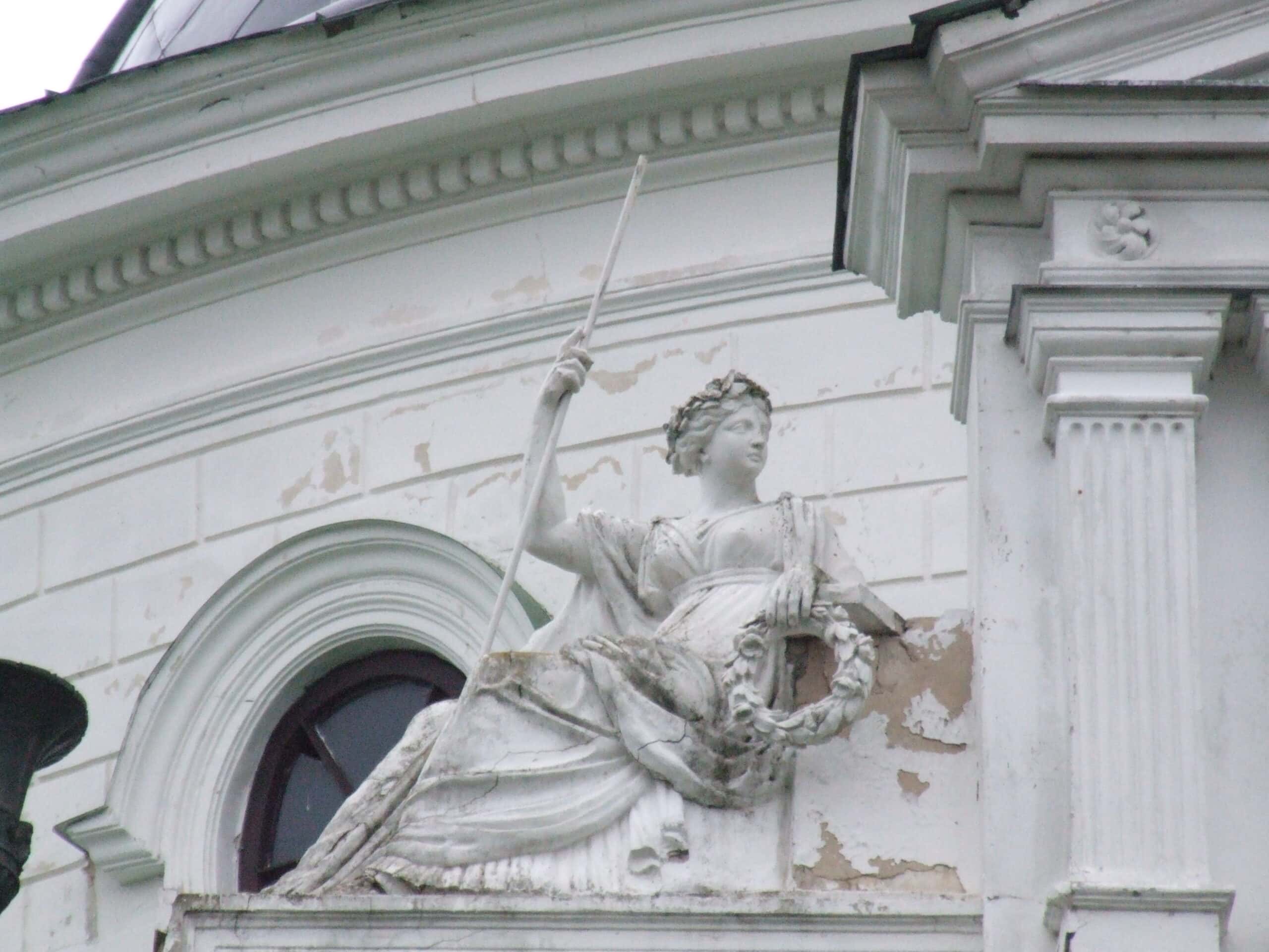 Барельєф жіночої фігури з мечем на історичній будівлі в Україні.